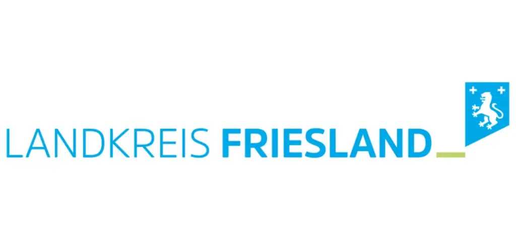 Logo mit dem Schriftzug 'Landkreis FRIESLAND' in blau—'Landkreis' in dünnerer, 'FRIESLAND' in fetter Schrift—rechts ein blaues, nach unten spitzes Wappen mit weißem Löwen und kleinen Kreuzen sowie einem kurzen grünen Strich.